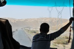 The road cuts right through a desert of sand dunes